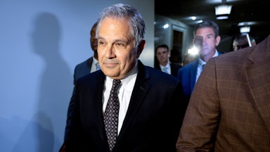 Larry Krasner walks in a hallway and smiles slightly.