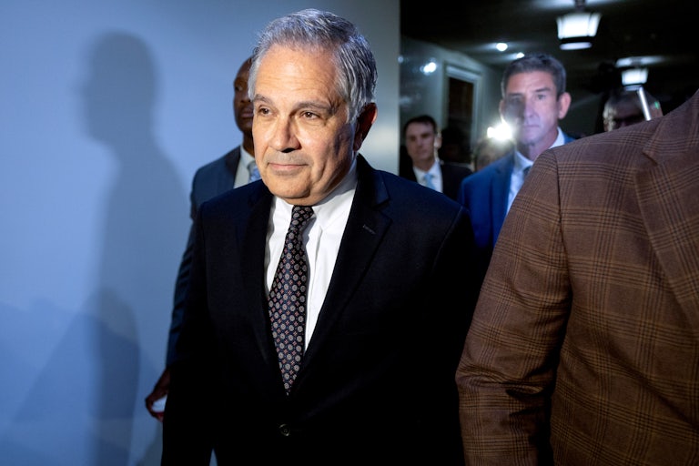 Larry Krasner walks in a hallway and smiles slightly.