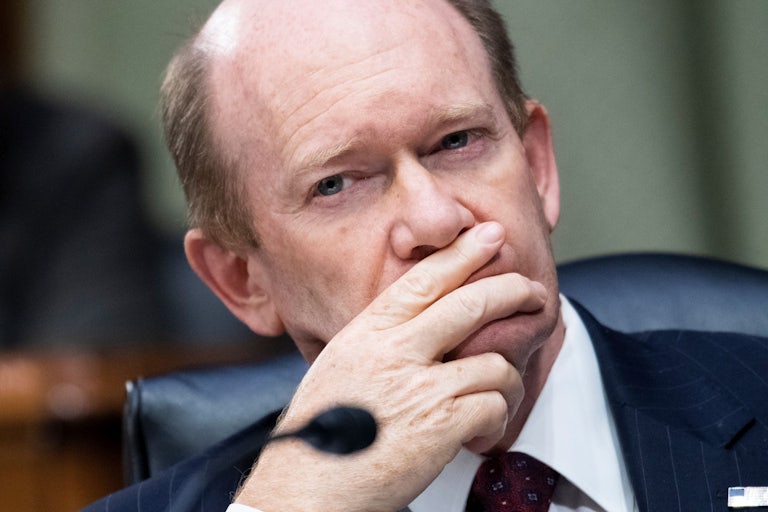 Chris Coons places his chin in his hand.