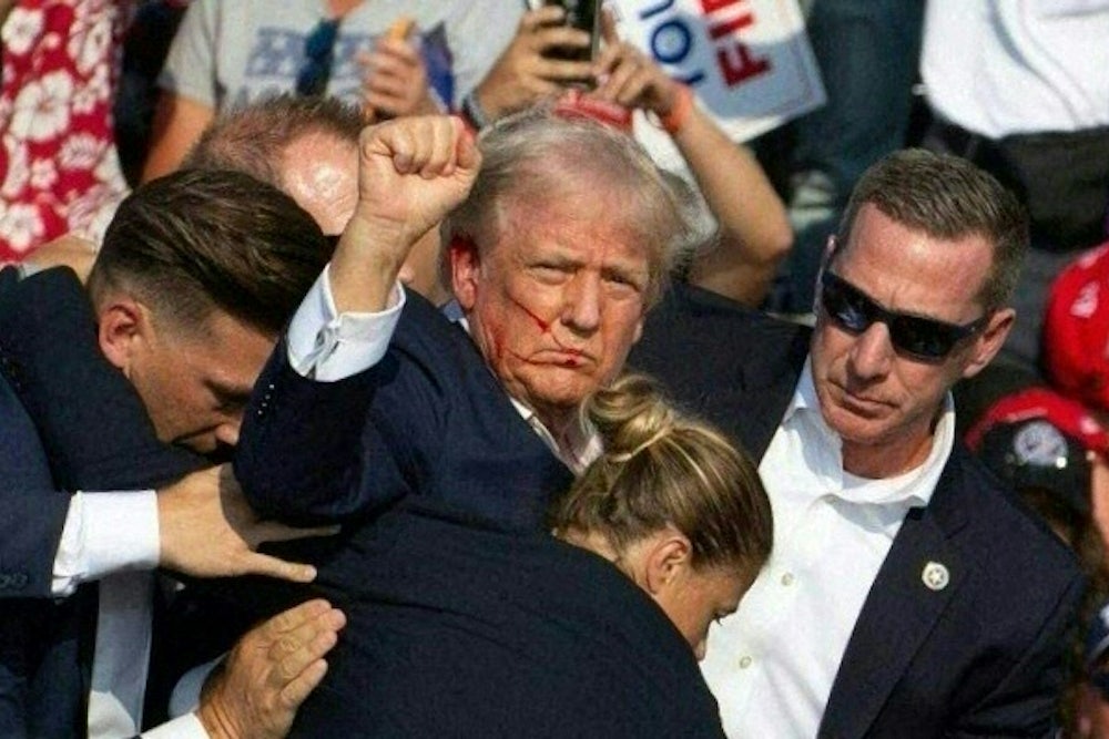 A bloodied and defiant Donald Trump raises a fist as Secret Service officers lead him off the stage after he was shot in the ear.