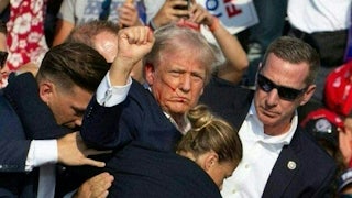 A bloodied and defiant Donald Trump raises a fist as Secret Service officers lead him off the stage after he was shot in the ear.