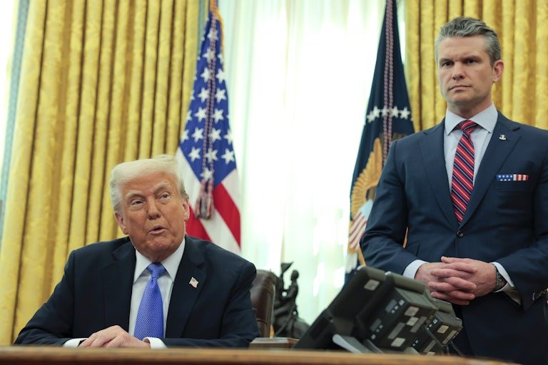 Donald Trump speaks to reporters while sitting at his desk in the Oval Office, as Defense Secretary Pete Hegseth stands next to him