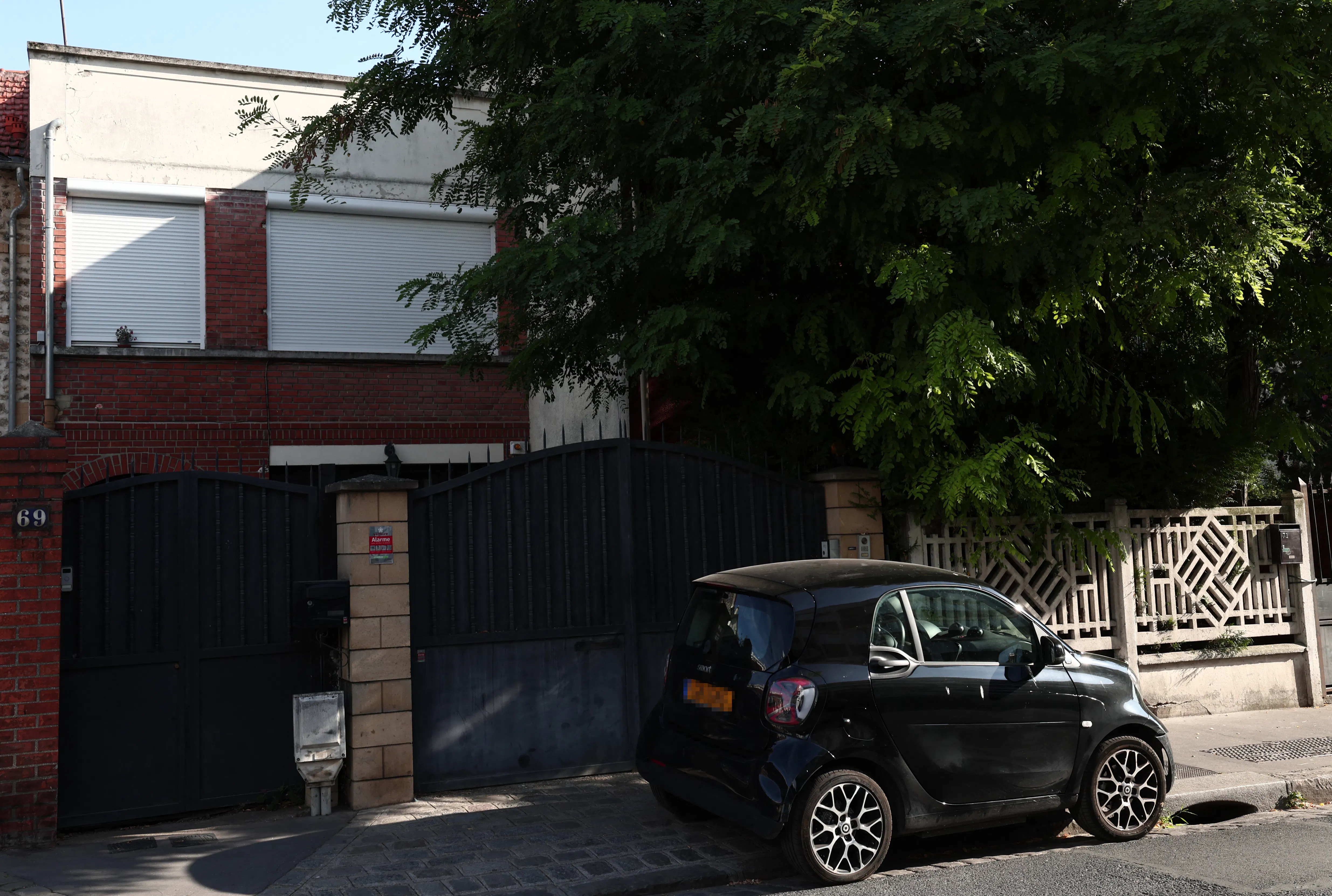 A small car parked in front of a gated home