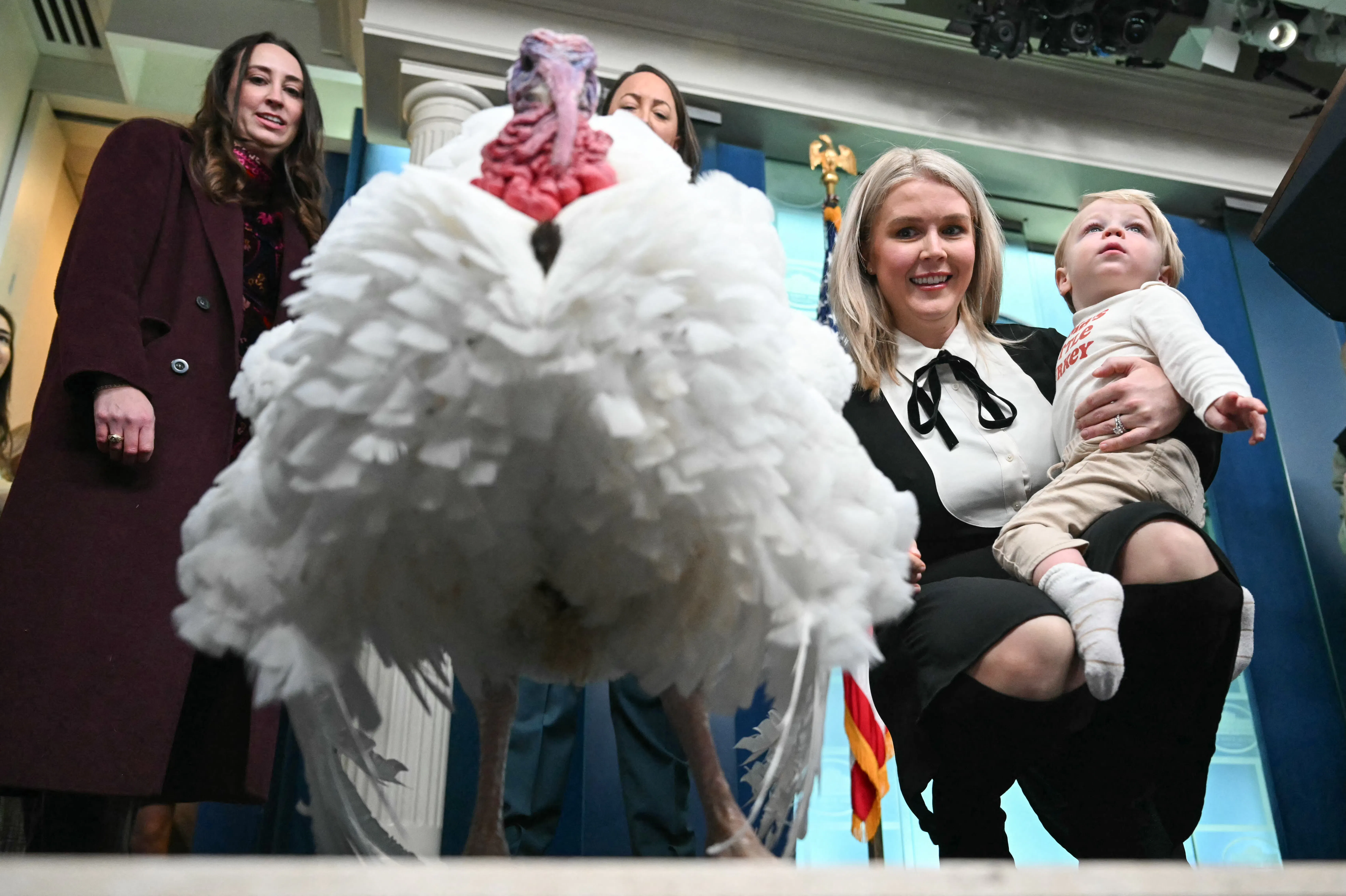 White House press secretary Karoline Leavitt holds her son as they look down at a turkey.
