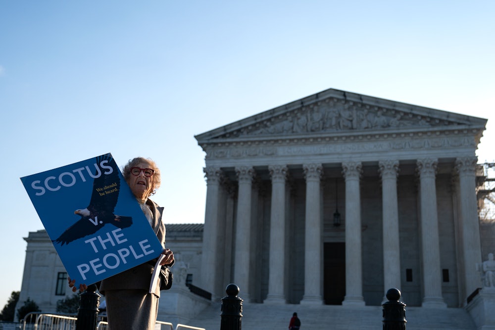 A woman holds a sign that reads "SCOTUS vs. the people" outside the Supreme Court.
