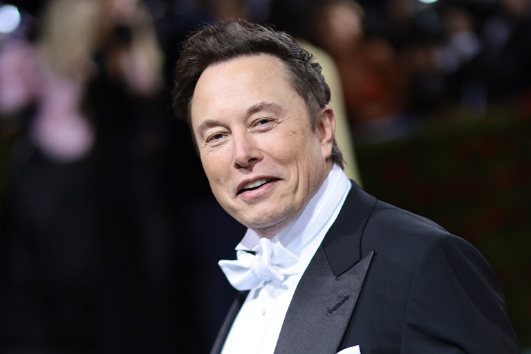 Elon Musk smiles nefariously while wearing a tuxedo.