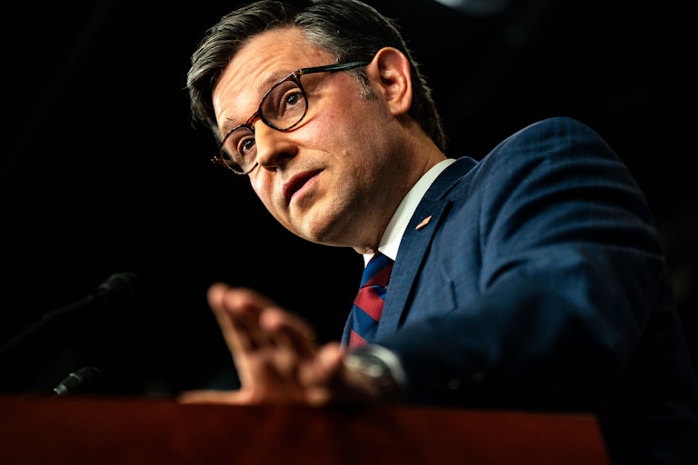 Mike Johnson speaking at a lectern and and holding his hand out