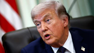 Donald Trump speaks while sitting at his desk in the Oval Office