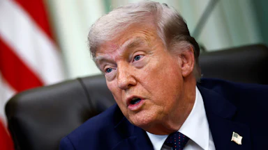 Donald Trump speaks while sitting at his desk in the Oval Office