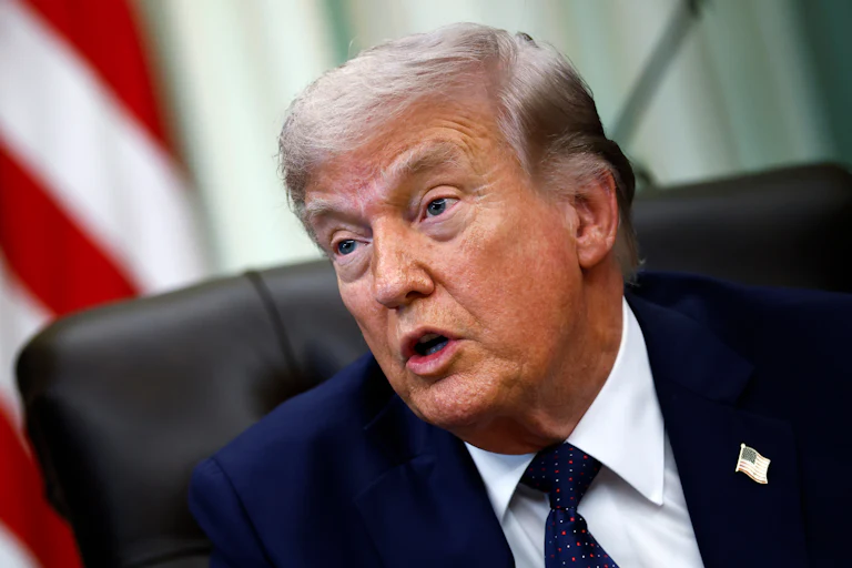 Donald Trump speaks while sitting at his desk in the Oval Office