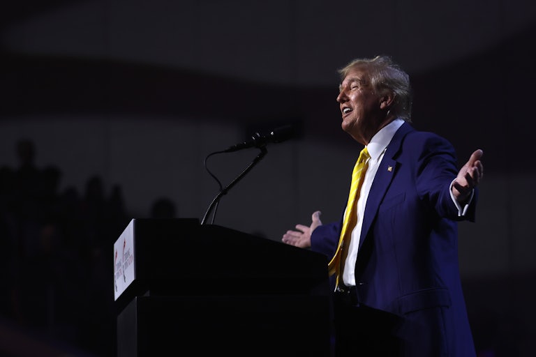 Donald Trump holds his arms out as he stands at a podium