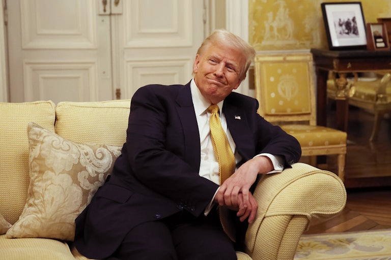 Donald Trump smiles while sitting on a couch