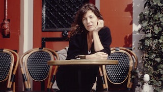 Jane Birkin at an outdoor café in Paris sitting at a bistro table with her dog at her feet
