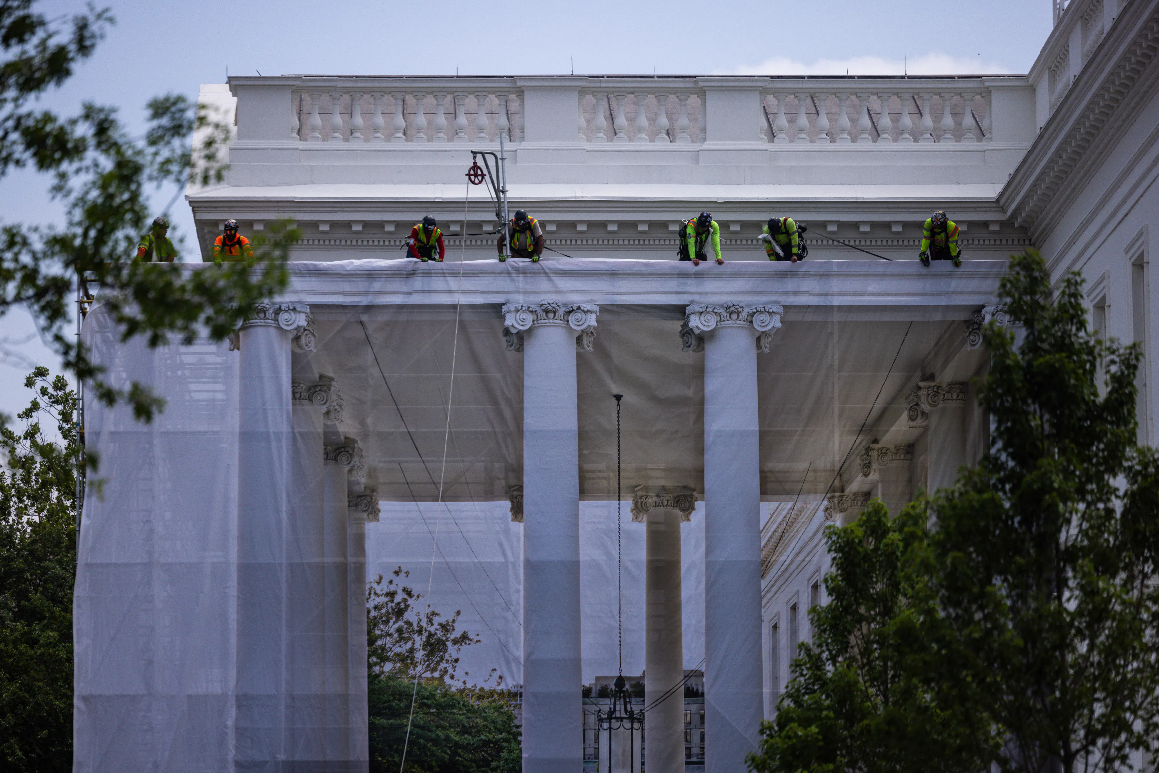 Workers hang a tarp printed with the North Portico on the White House