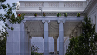 Workers hang a tarp printed with the North Portico on the White House