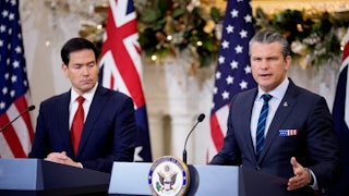 State Secretary Marco Rubio and Defense Secretary Pete Hegseth stand at podiums next to each other. Hegseth is speaking.