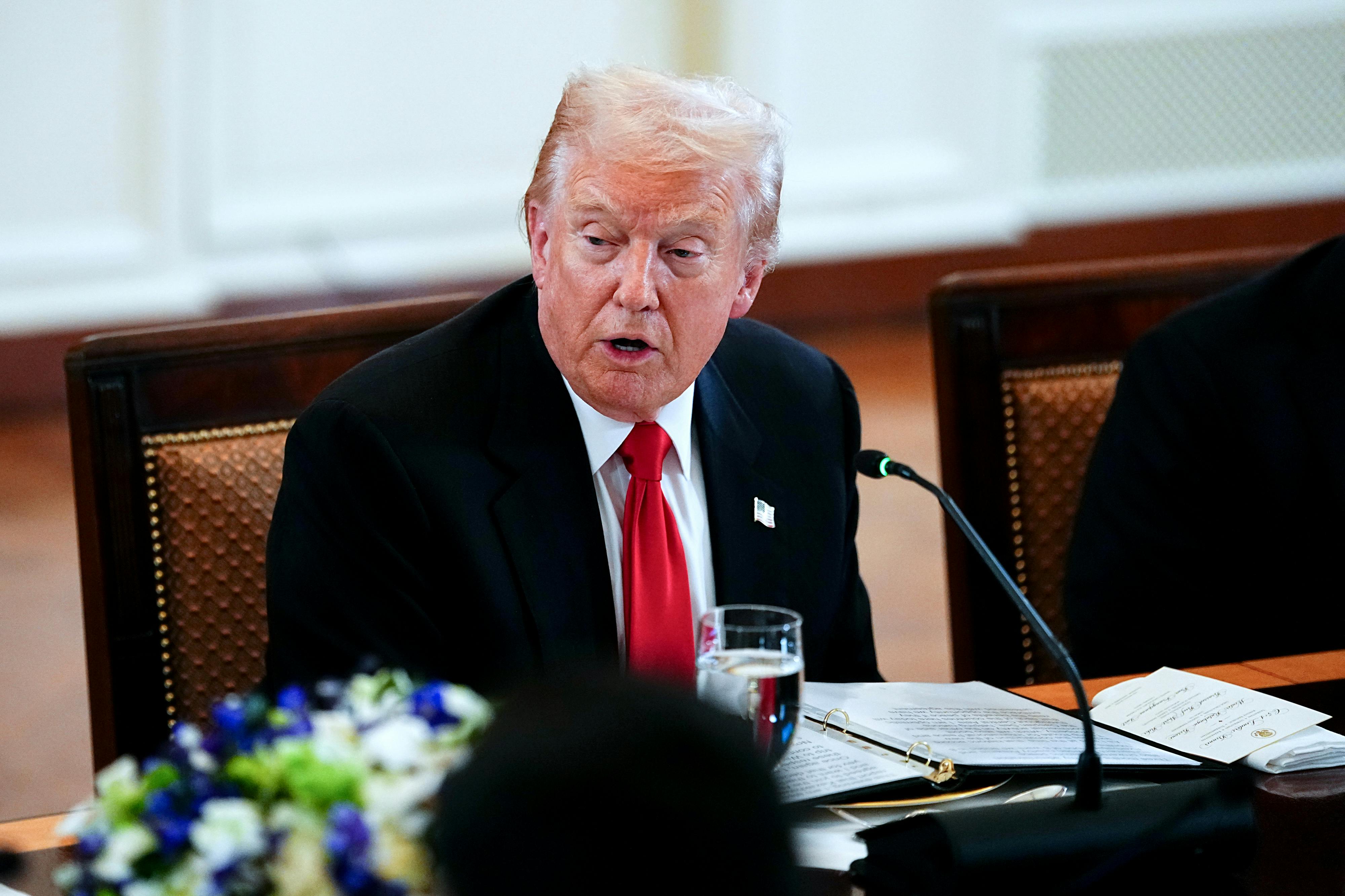 Donald Trump speaks while sitting at a table