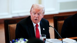 Donald Trump speaks while sitting at a table