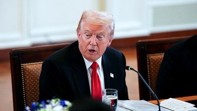 Donald Trump speaks while sitting at a table
