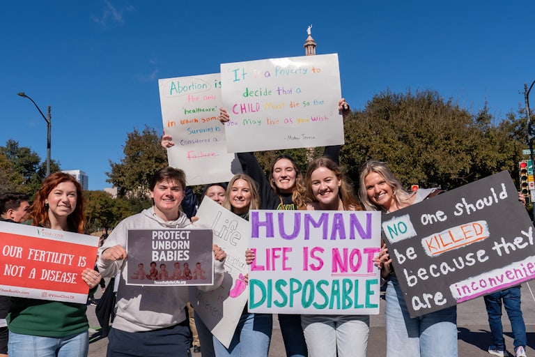 Demonstrators hold anti-abortion signs.