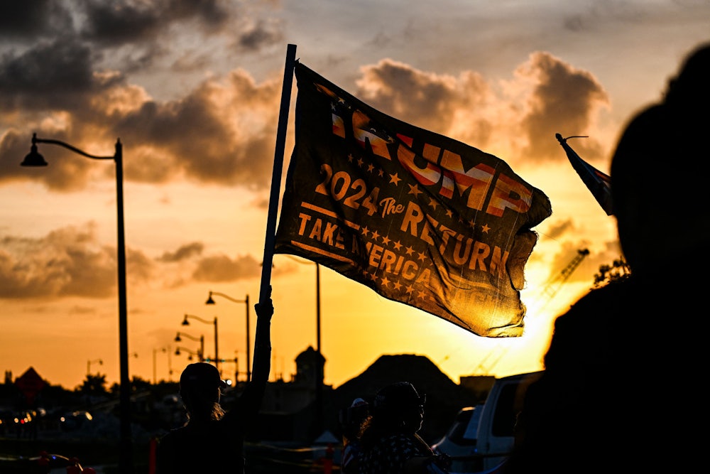 A supporter waves a flag reading "Trump 2024 the Return."