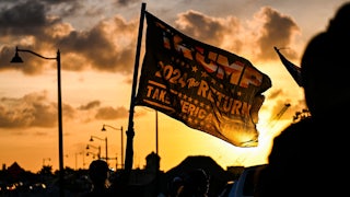 A supporter waves a flag reading "Trump 2024 the Return."