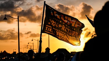 A supporter waves a flag reading "Trump 2024 the Return."