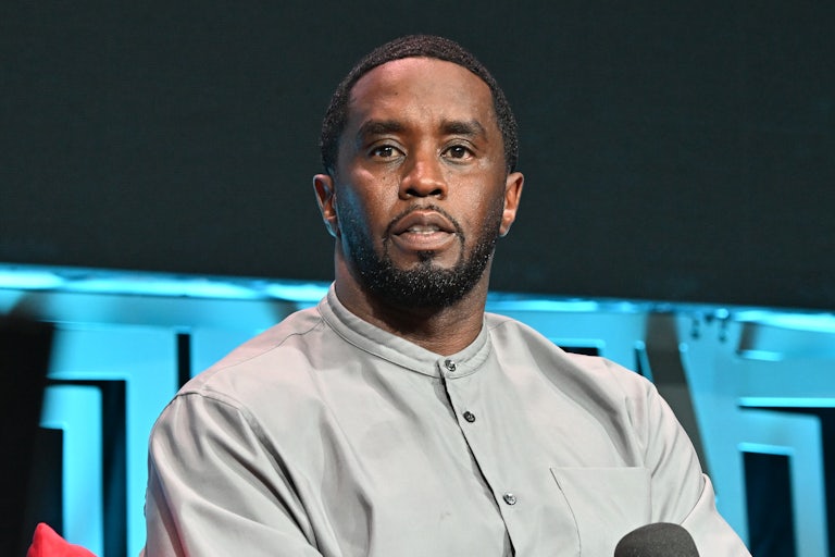 Sean "Diddy Combs holds a mic while seated on stage.