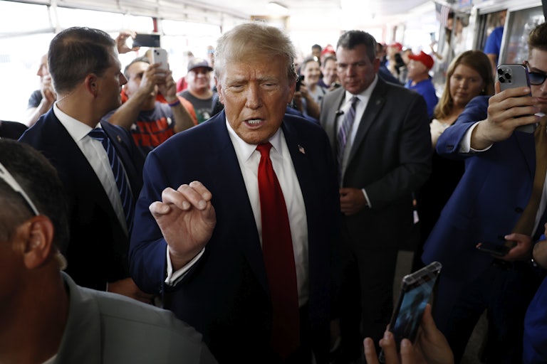 Donald Trump speaks in a crowd, eyes narrowed and making a hand gesture