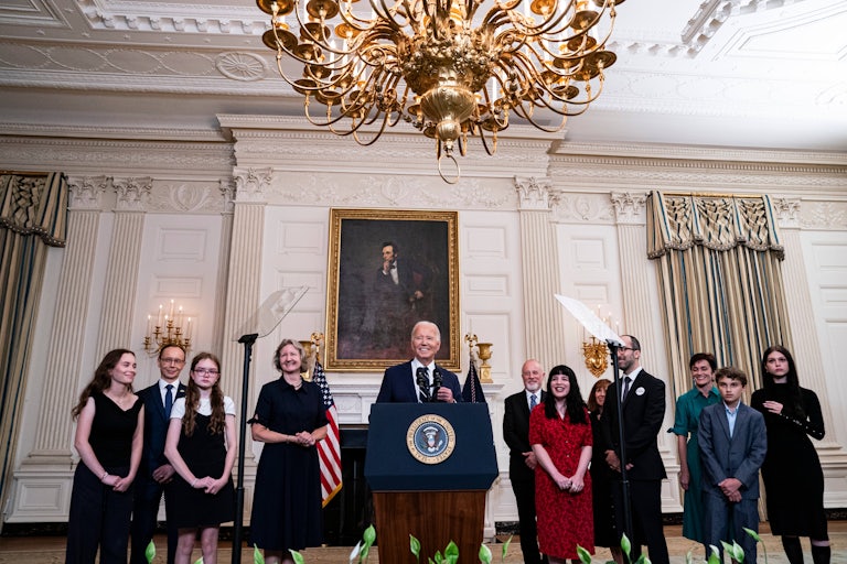 Joe Biden stands at a podium, surrounded by family members of the American citizens and green card-holder freed in the Russian prisoner exchange