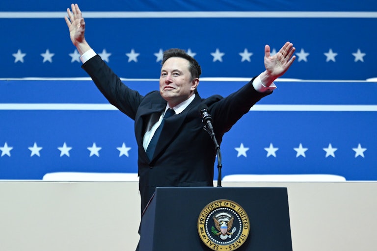 Elon Musk holds his arms above his head while on stage at Donald Trump’s inauguration parade