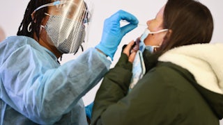 A health care worker swabs a person's nose.