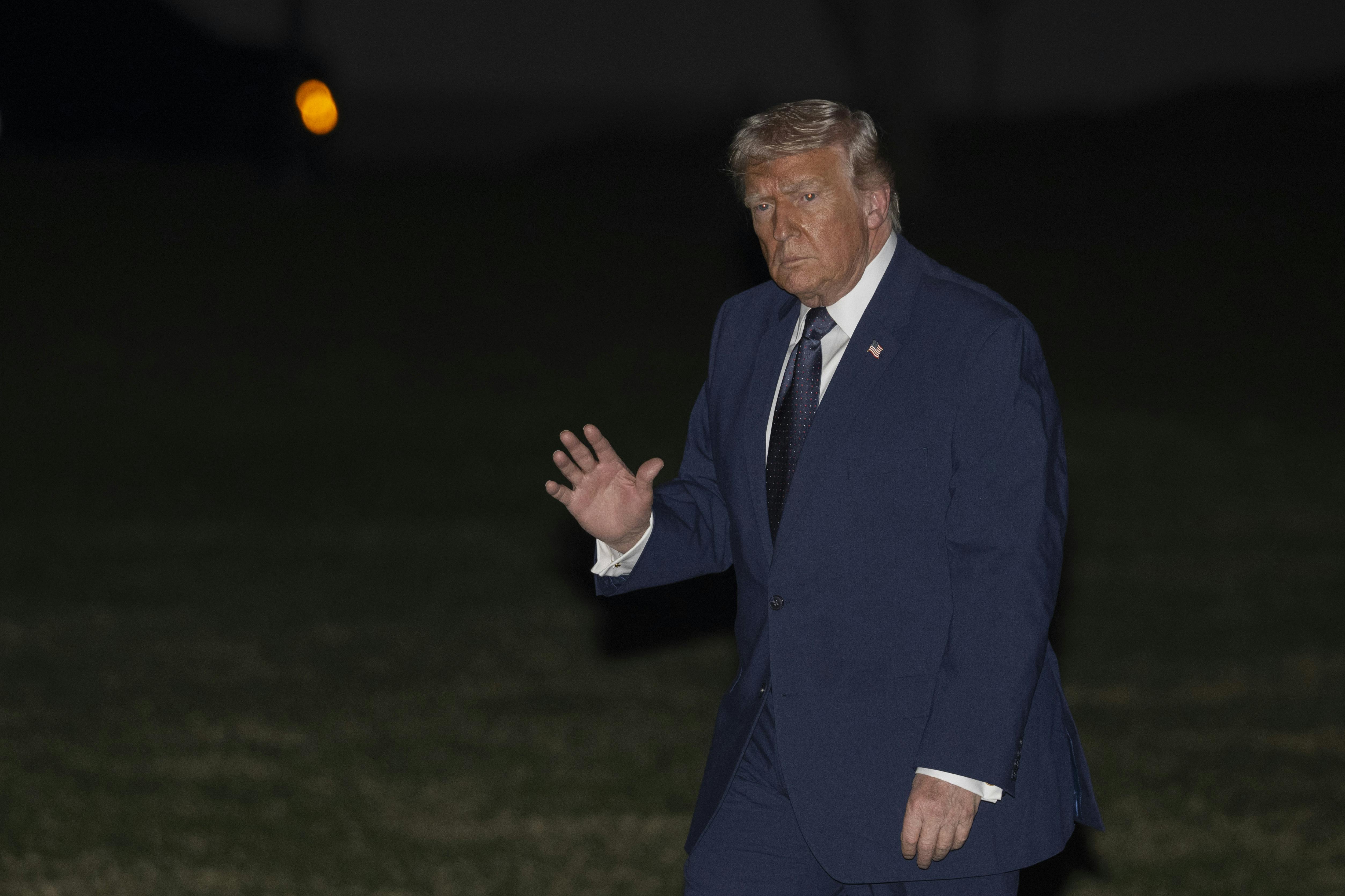 Donald Trump waves while walking outside the White House
