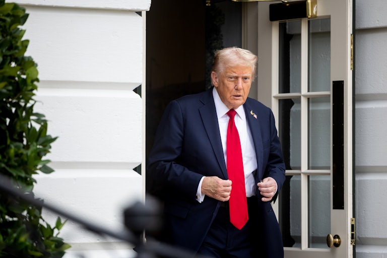 Donald Trump adjusts his suit jacket while walking out of the White House
