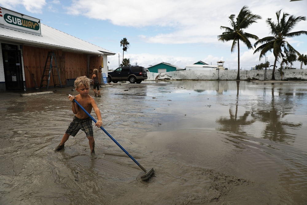 A child attempts to sweep away flood waters.