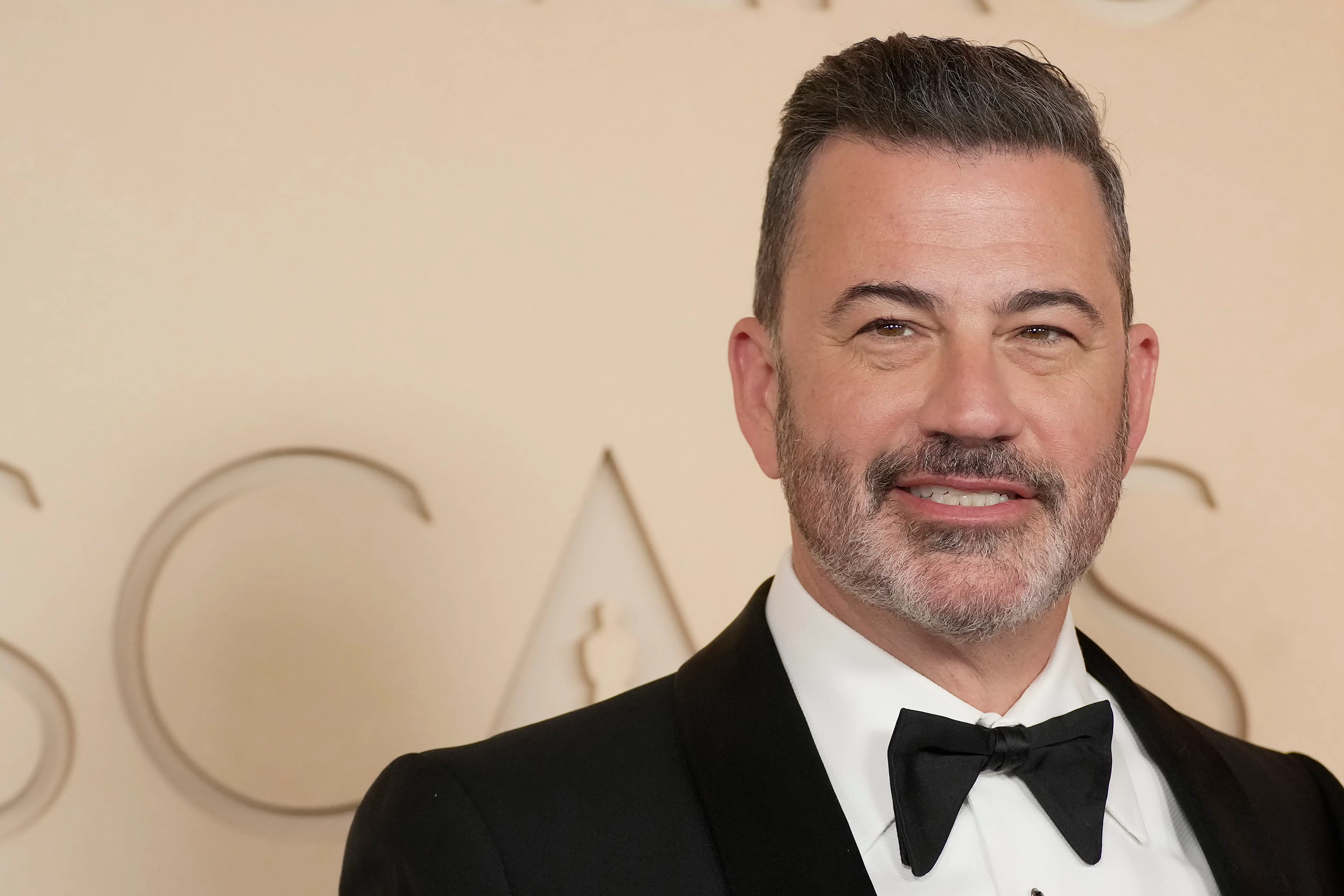 Jimmy Kimmel smiles while standing on the red carpet at the Oscars