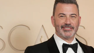 Jimmy Kimmel smiles while standing on the red carpet at the Oscars