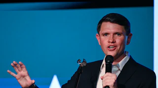 James Talarico gestures with one hand and speaks into a microphone he holds with the other