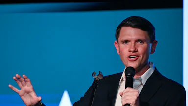 James Talarico gestures with one hand and speaks into a microphone he holds with the other