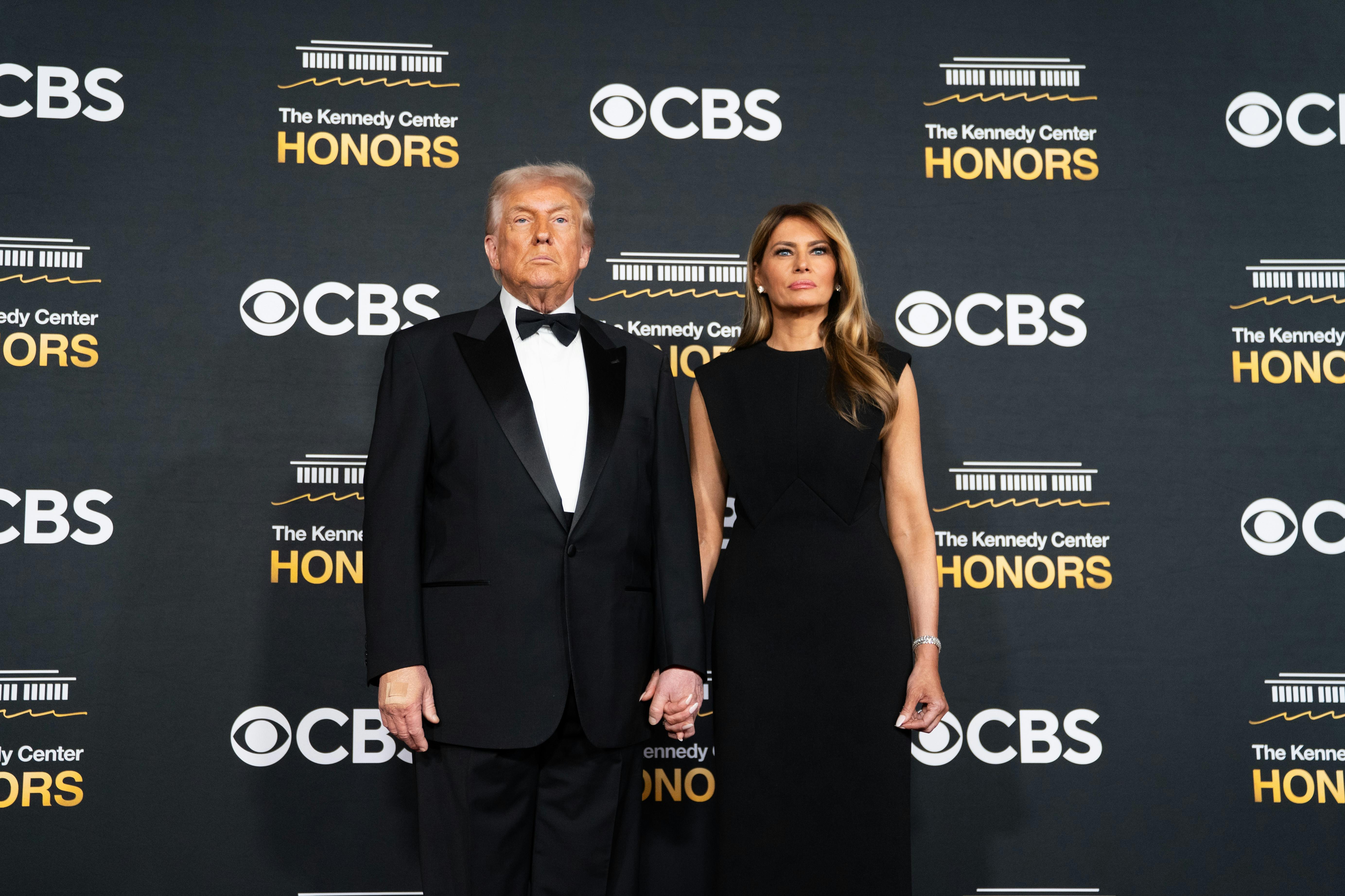 Donald and Melania Trump stand in front of a backdrop that reads "CBS" and "Kennedy Center Honors."