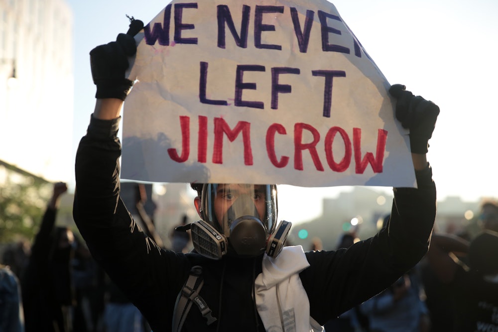 A protester holds up a sign that reads "We Never Left Jim Crow" during a protest.