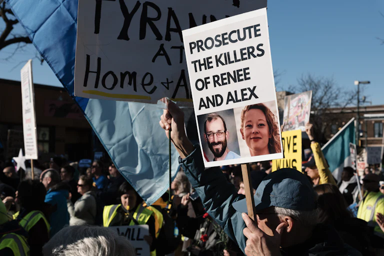 A person holds a sign that says, "Prosecute the killers of Renee and Alex," with photos of Renee Nicole Good and Alex Pretti, during an anti-ICE protest in Minneapolis.