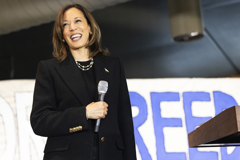 Kamala Harris smiles while holding a microphone