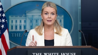 Karoline Leavitt raises a finger while speaking at the podium in the White House press briefing room