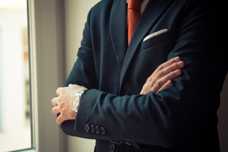 man in a suit crosses his arms (can't see the person's face)