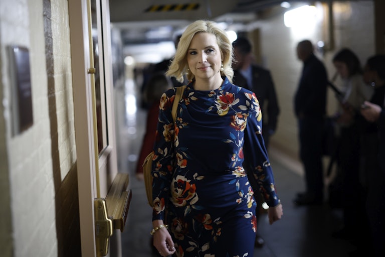 Iowa Rep Ashley Hinson wears a flower dress and walks through the hall of the Capitol