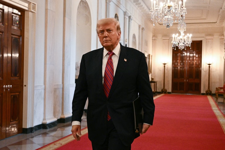 Donald Trump walks n a red carpet in the White House.