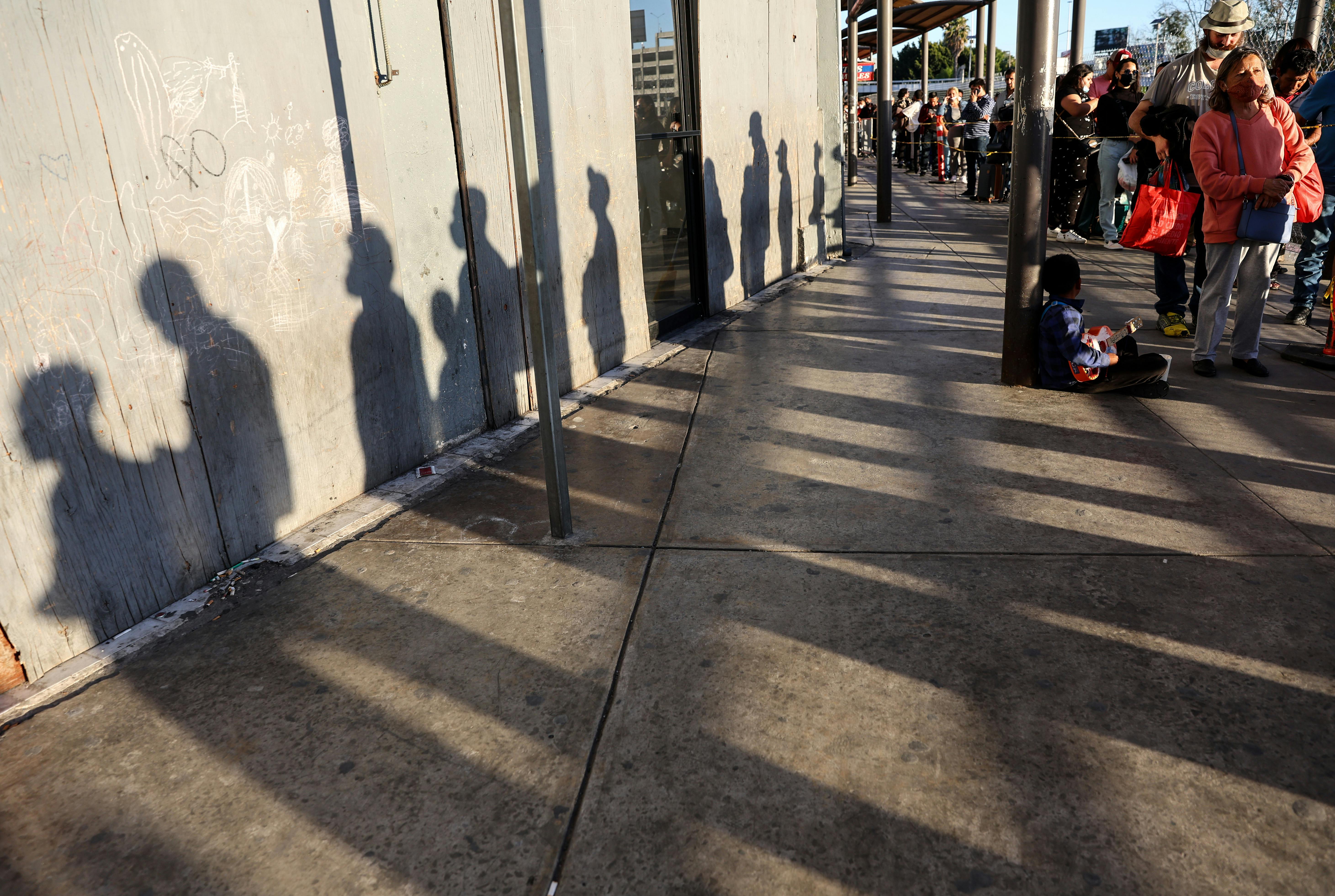 People wait in line on their way to cross the southern border into the United States near the San Ysidro Port of Entry in Tijuana, Mexico.