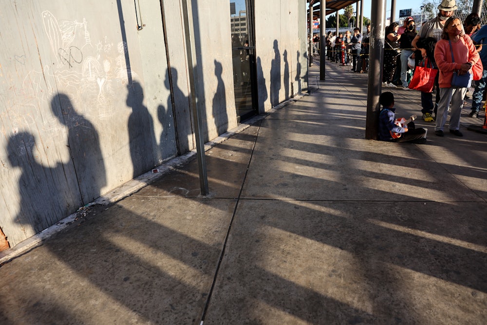 People wait in line on their way to cross the southern border into the United States near the San Ysidro Port of Entry in Tijuana, Mexico.