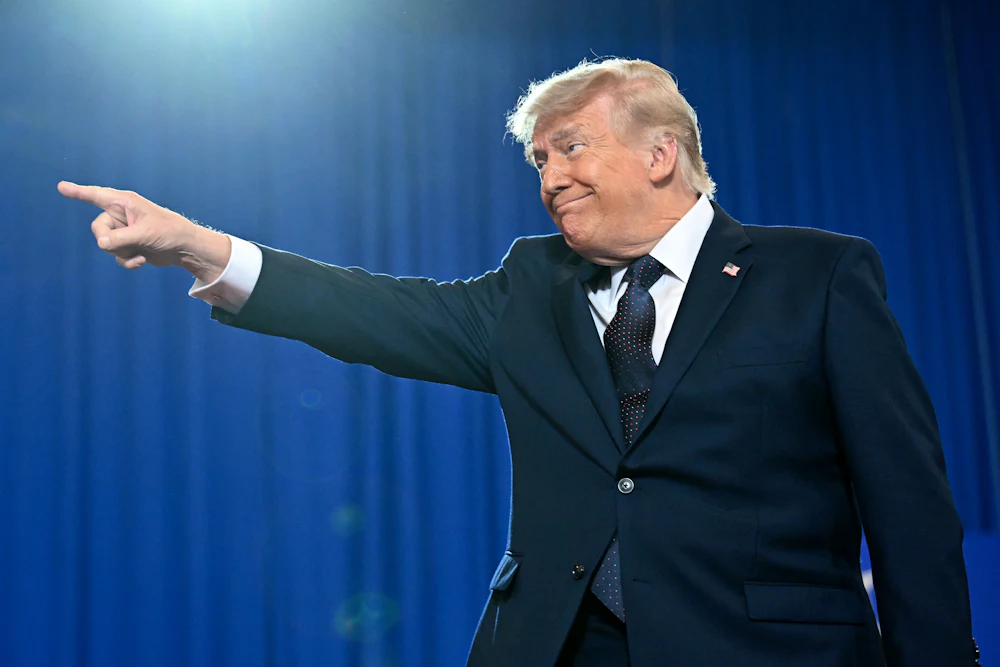 Trump grins as he points a finger to his right